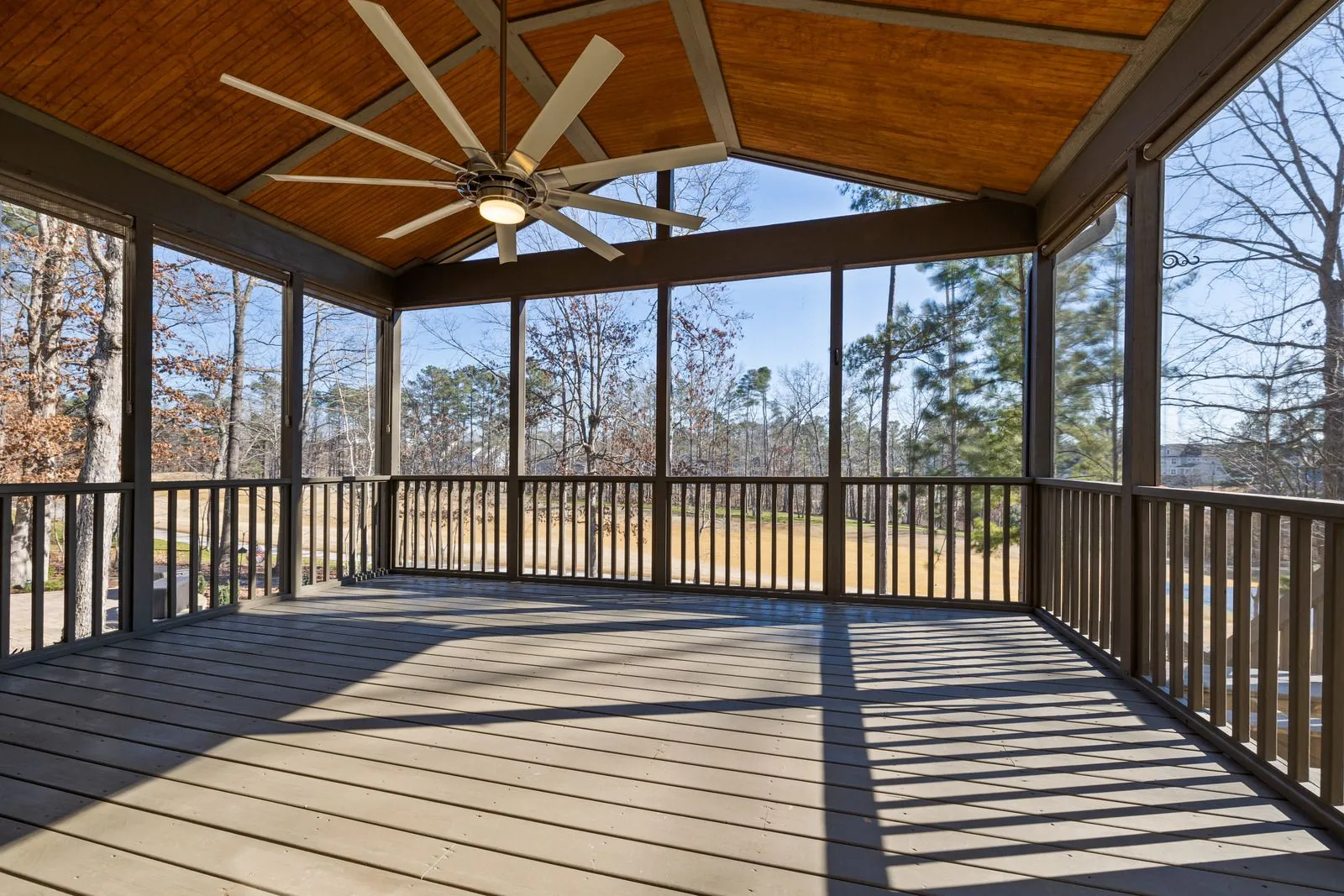 Spacious screened porch with wood ceiling, ceiling fan, durable decking, and scenic backyard views,  