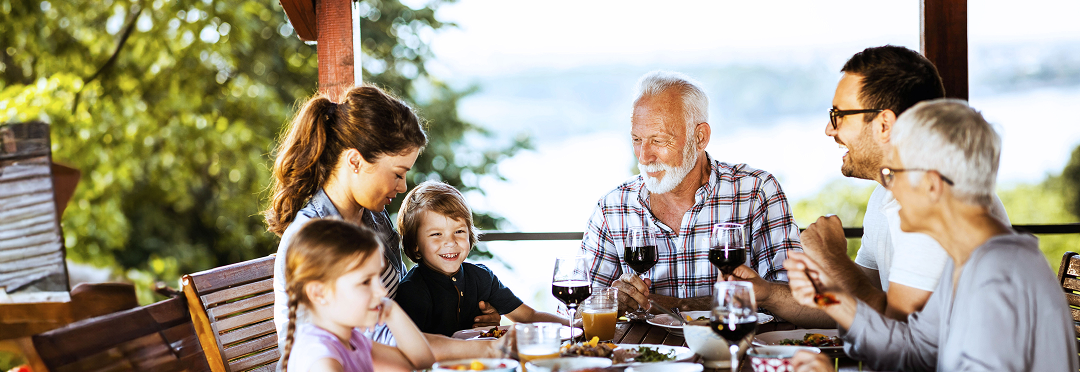 A multigenerational family eating dinner outside.