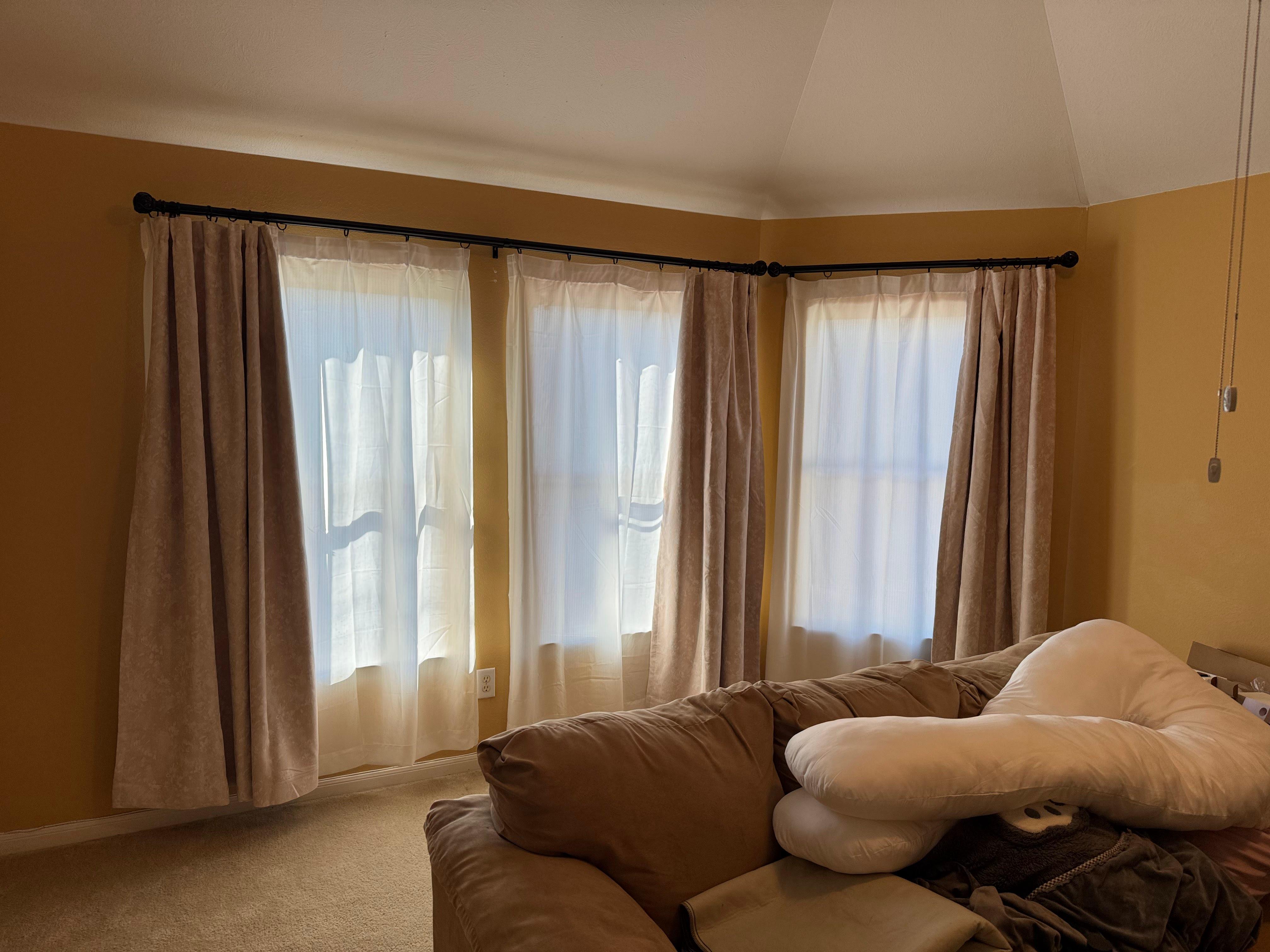 Curtains installed over three windows in a residential living area.