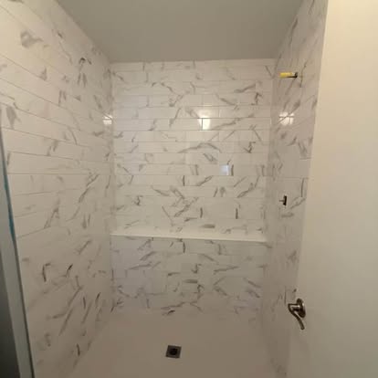 Completed marble-look tile shower with a coordinated shower floor and drain. 