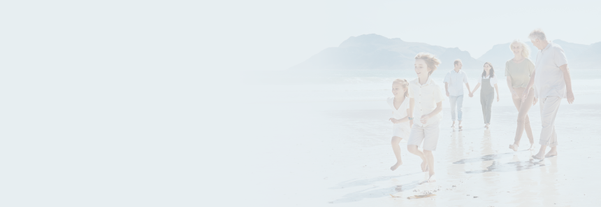 A multigenerational family walking along the beach together.