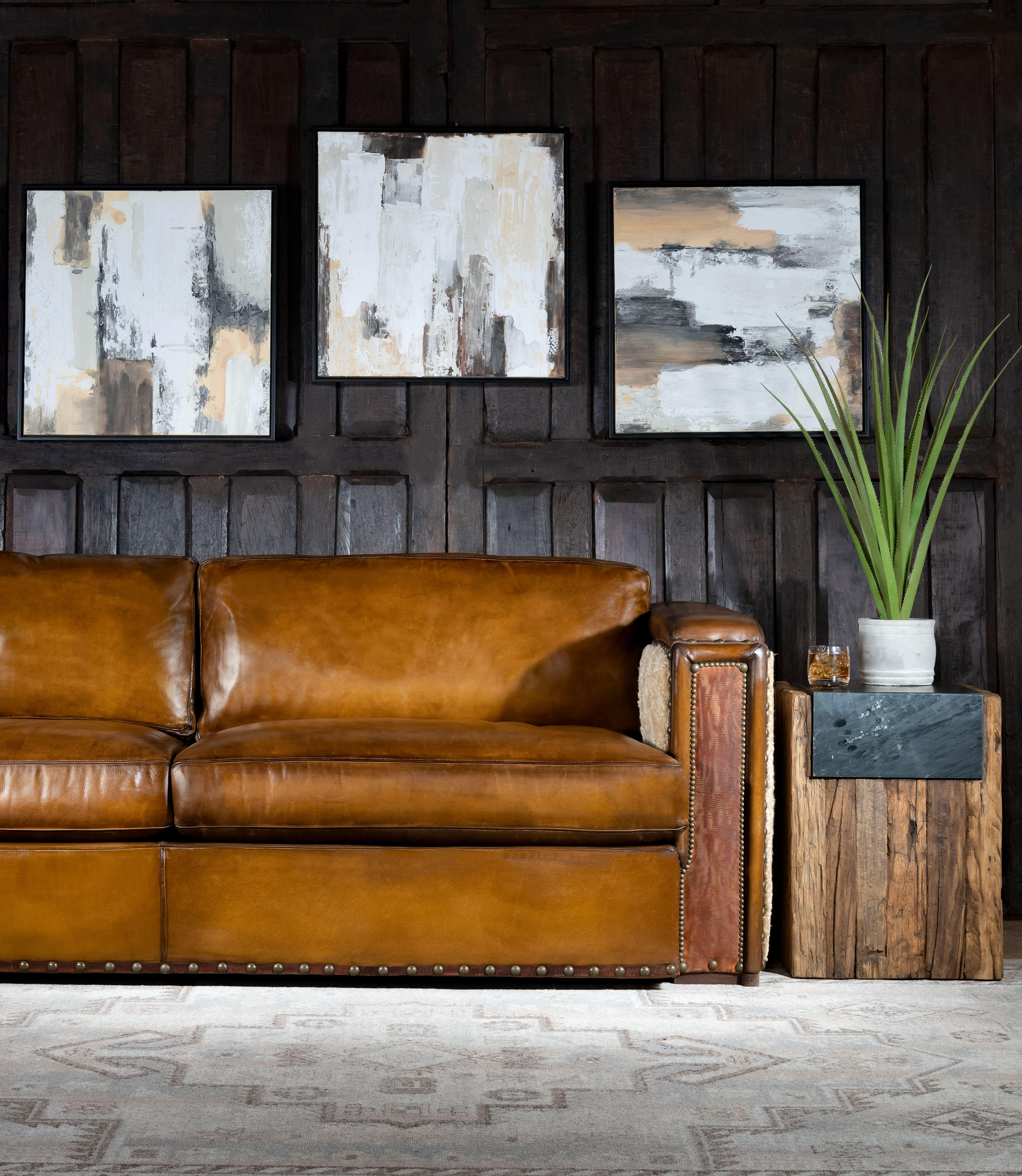 Our Cowboy Architect Sofa is modern rustic style with timeless comfort and quality. Featuring a hand burnished leather to achieve an aged patina in just the right places to reflect the aged qualities only time, wear, and frequent care could have accomplished naturally. The large boxy arms and studded genuine brass nail heads add that rustic feel while maintaining a modern design. The plush pillow back provides a sofa, sink in comfort that is great for relaxing. Premium Shearling hides wrap around the sides and back, accented with a thick leather belting. Black walnut is hand cut, sanded, and oiled rubbed for the finishing on the legs. The stylish looks and comfort of the Cowboy Architect Leather Sofa is top of the line inside and out! Constructed with a hardwood frame and topped off with a high density foam cushion ensures lasting comfort and durability. 100% American Made to the highest quality of standards and craftsmanship!