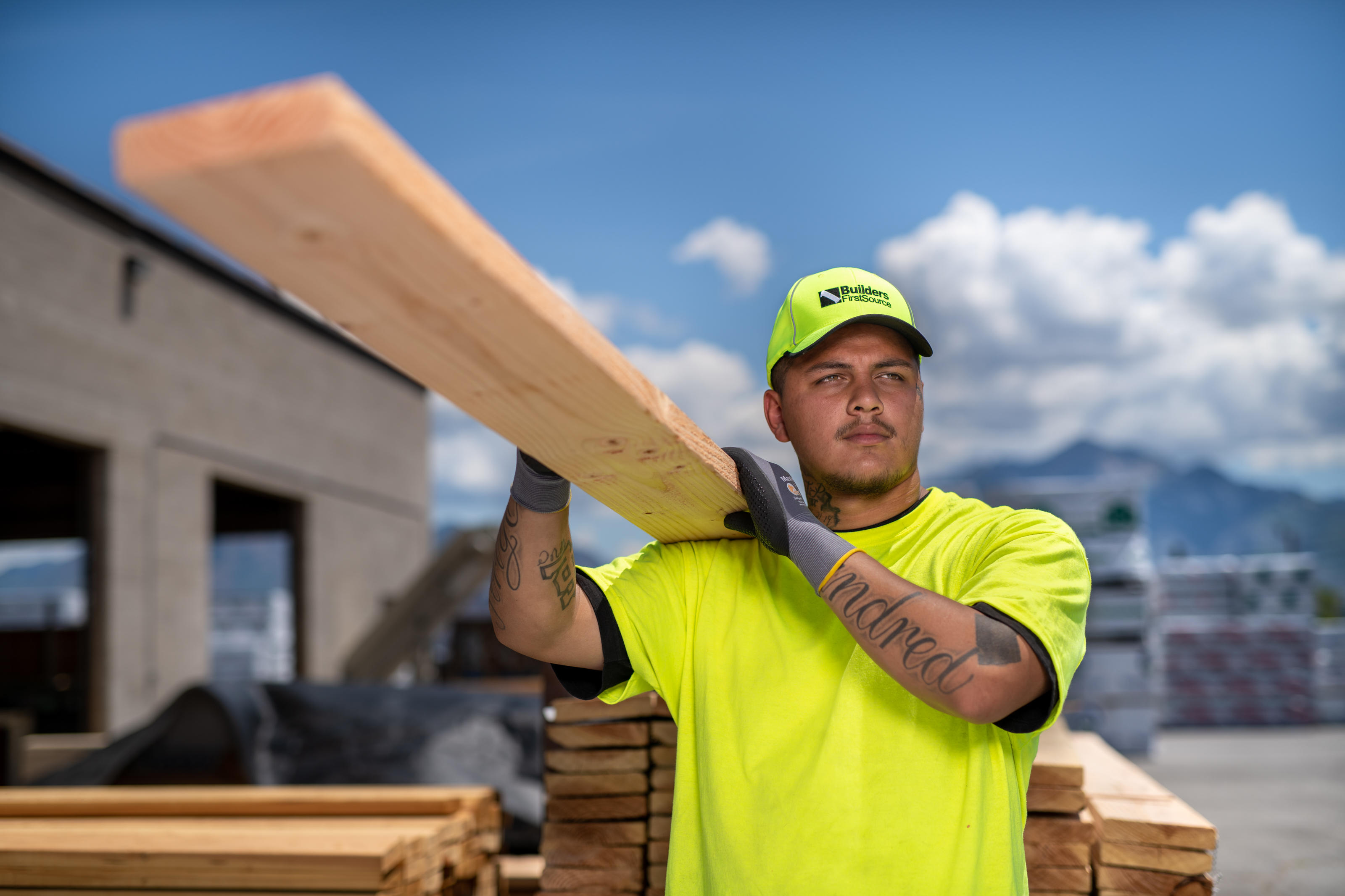 Builders FirstSource employee carrying lumber at building materials store.