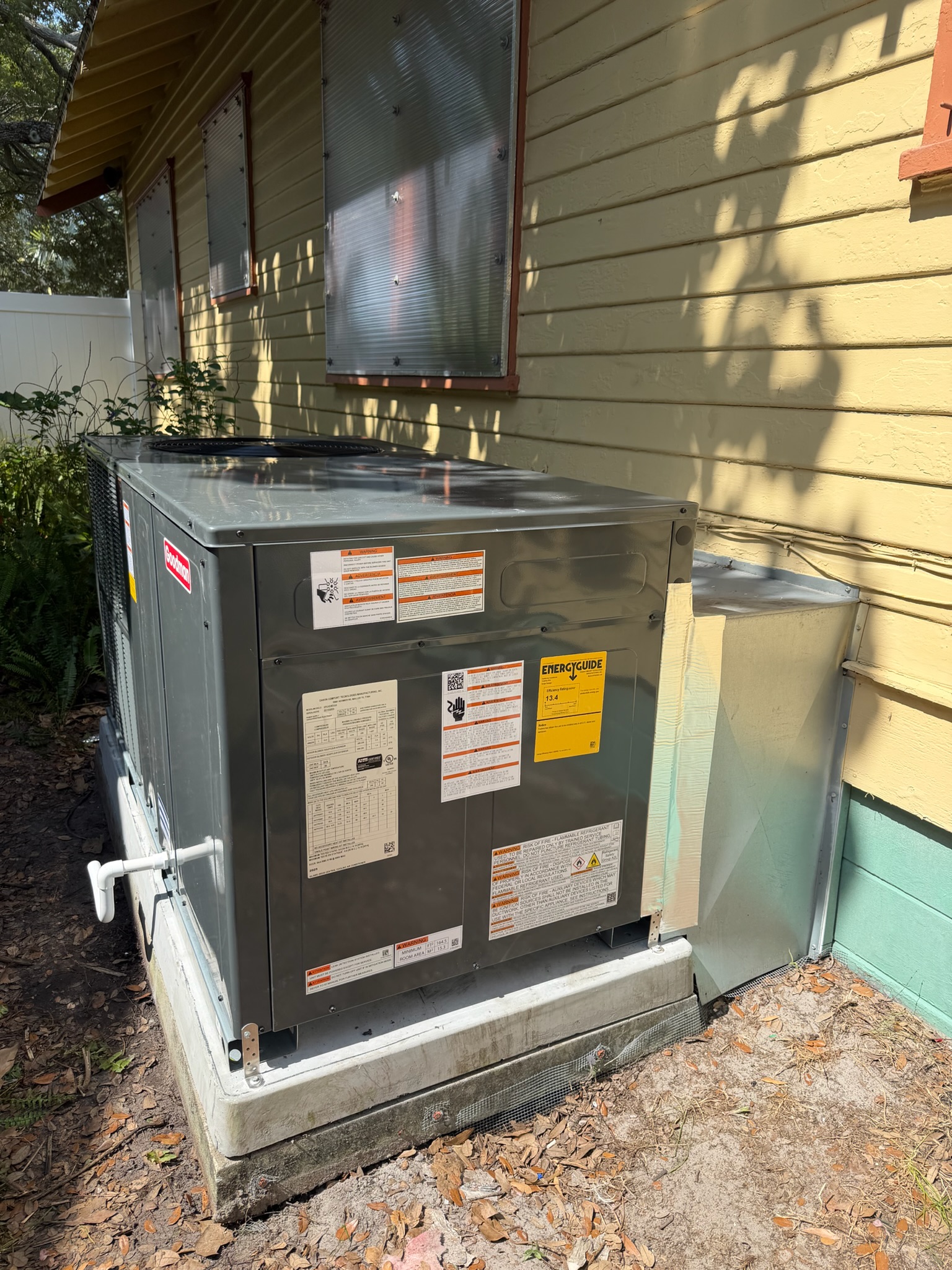 Outdoor residential air conditioning unit positioned beside a home as part of a central HVAC system. 