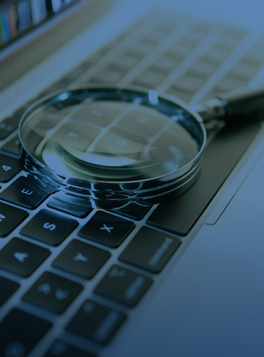 A magnifying glass resting on a laptop keyboard.