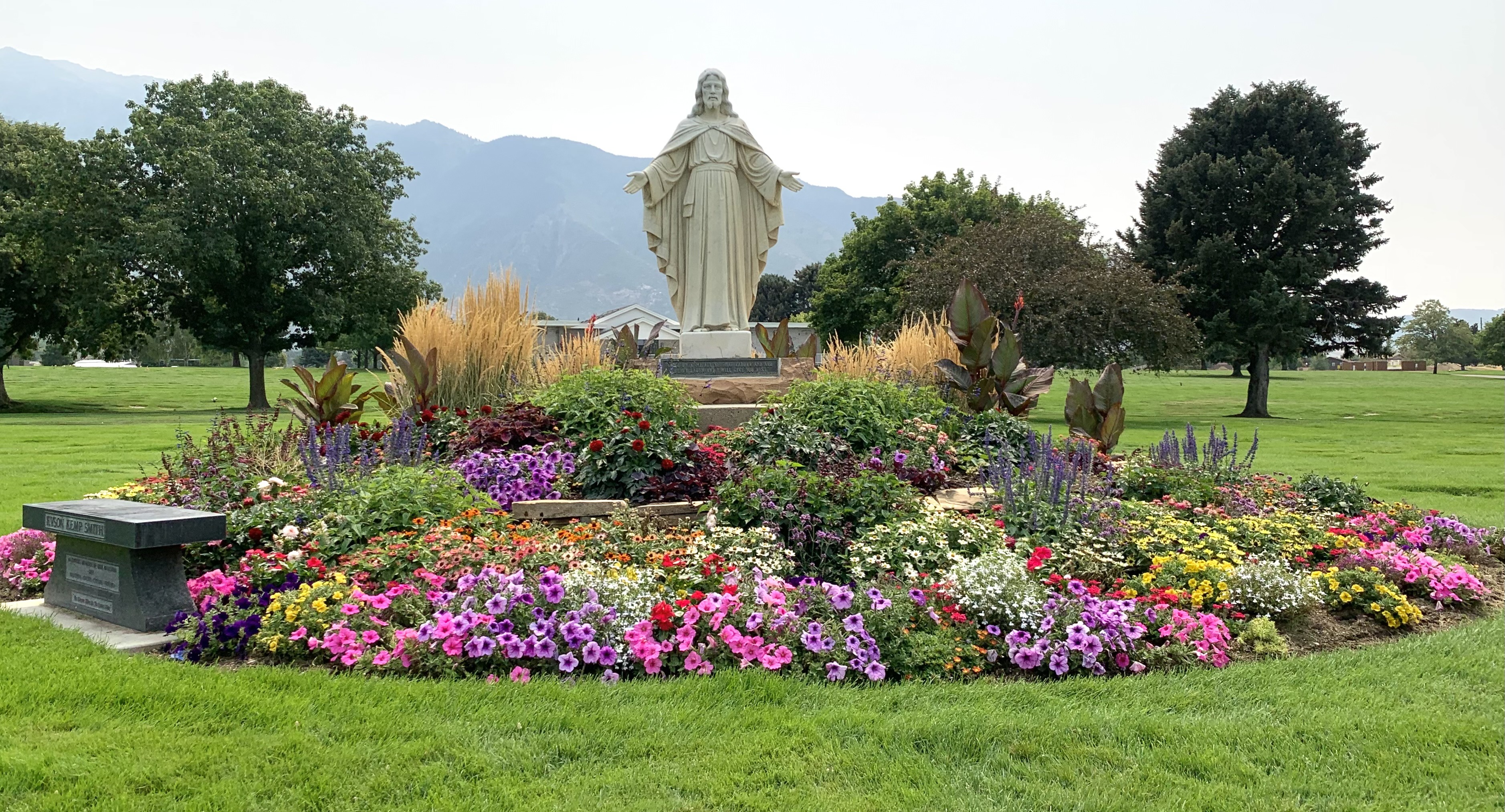The Christus statue at the heart of Larkin Sunset Gardens in Sandy, set in a round bed of summer flowers on the cemetery lawns.