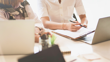 Close-up of a client and advisor filling out forms together.