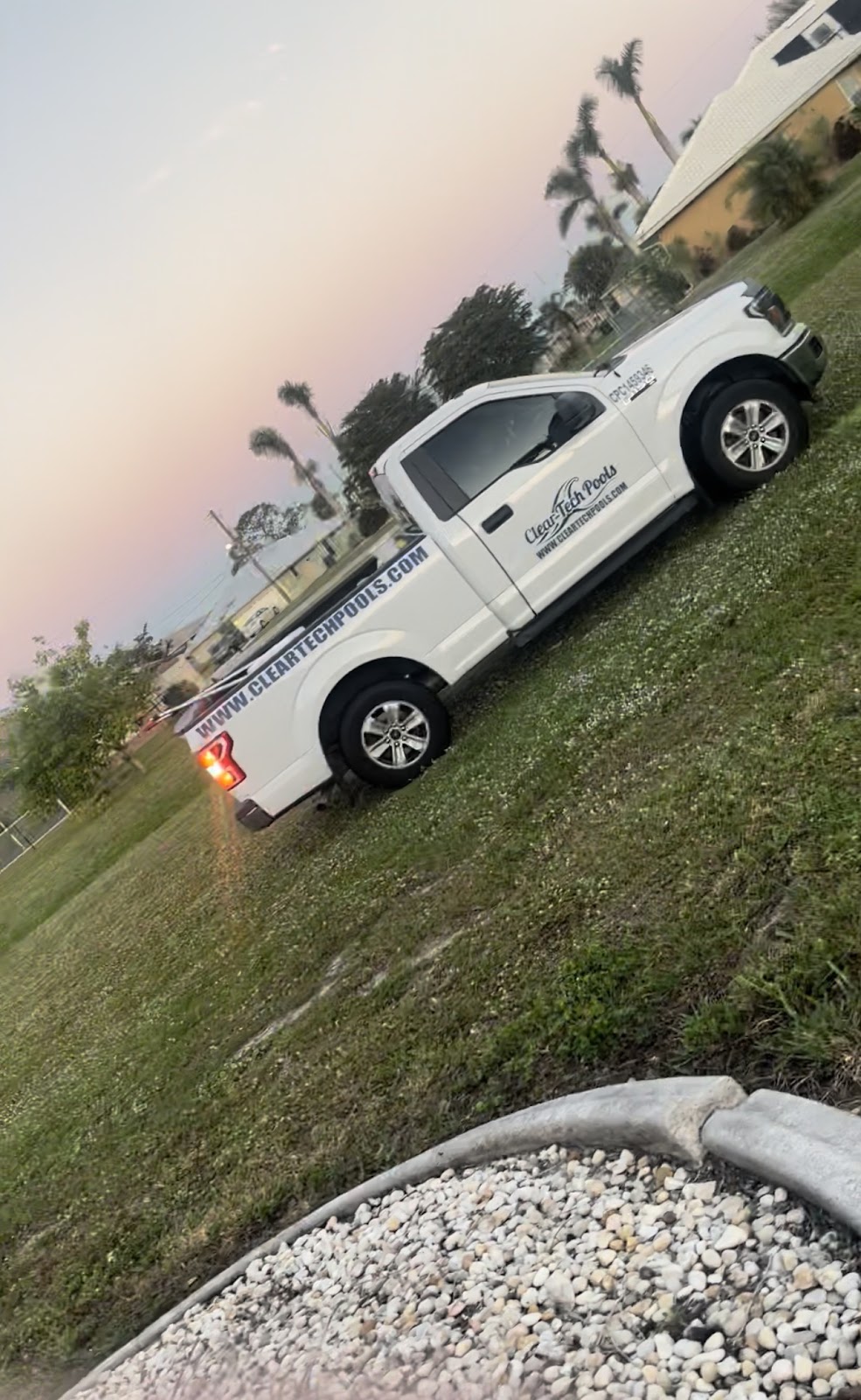 Pool service truck parked on a grassy residential property during an evening service visit.