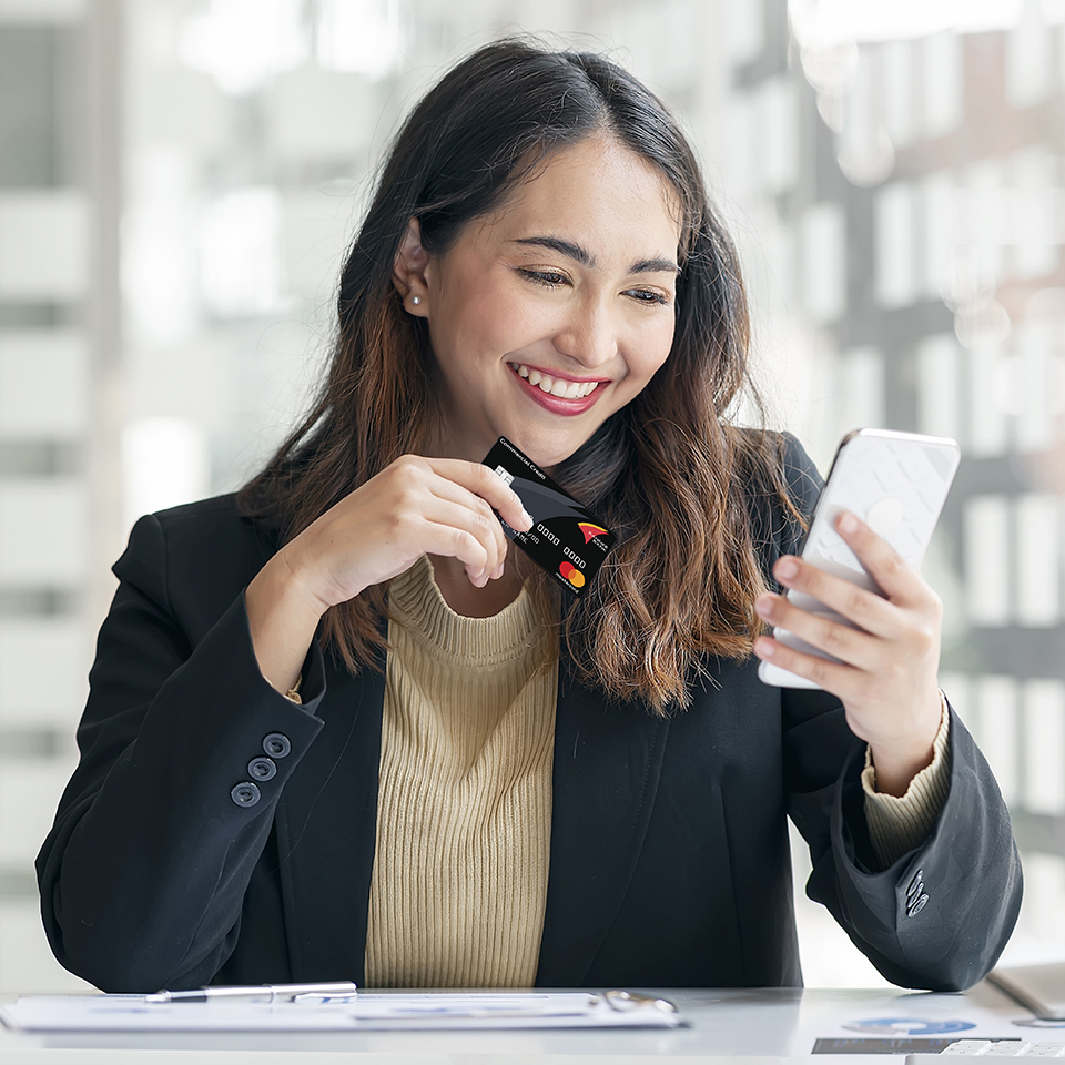 A woman holding a Banner Bank credit card looking at a phone