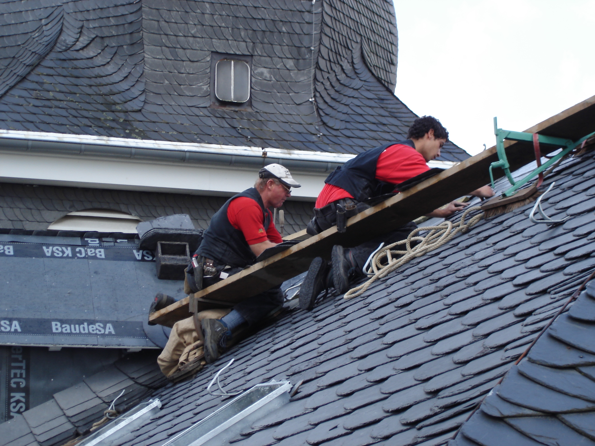 Das Dach einer denkmalgeschützten Kirche in Leverkusen wird mit Schiefer in altdeutscher Deckung neu eingedeckt.