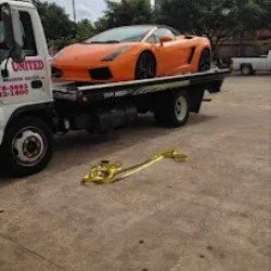 United Roadside Service carefully transports an orange Lamborghini on a flatbed tow truck, delivering premium vehicle care, secure loading, dependable towing, professional transportation, and trusted roadside assistance across Houston.