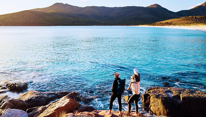 Two people at the shore of a lake.