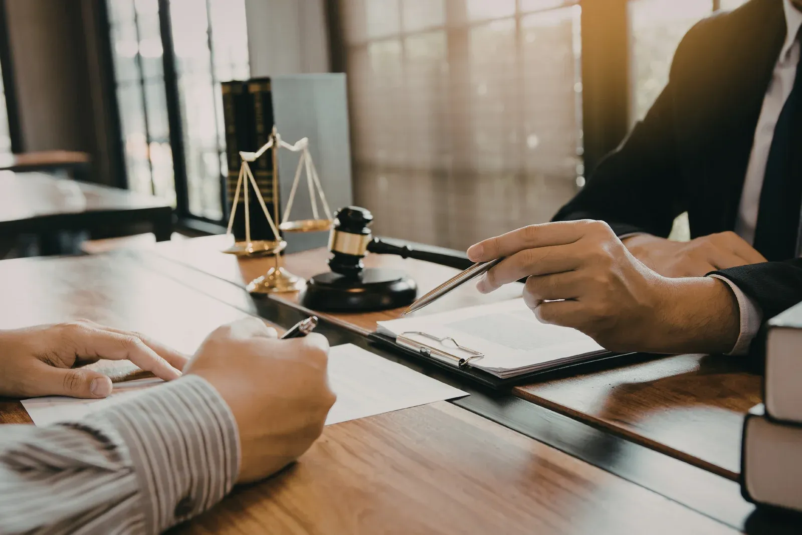Professional signing meeting showing a client and legal expert reviewing documents at a desk, with gavel and scales visible, representing legal compliance, contract finalization, and secure real estate closing process.