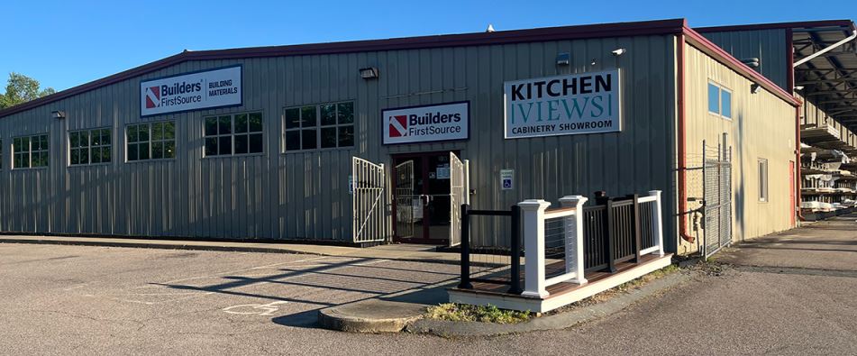 Exterior view of a Builders FirstSource building materials store and Kitchen Views cabinetry showroom. The store provides high-quality lumber, cabinets, and construction materials for contractors, builders, and homeowners. The parking lot offers convenient access to a wide range of building supplies and home improvement products.