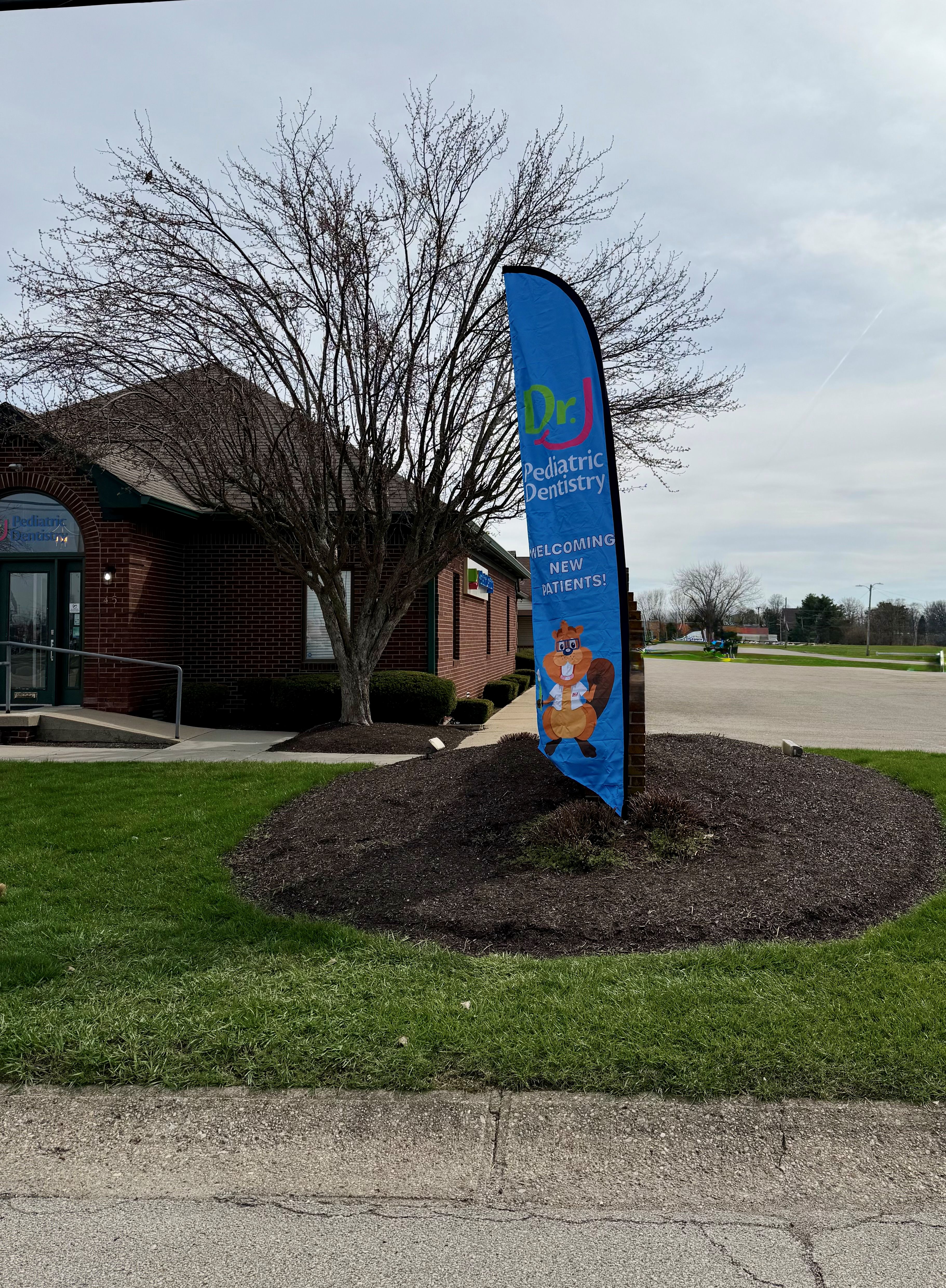 'New Patients Welcome' flag outside the Dr. J Greenfield office