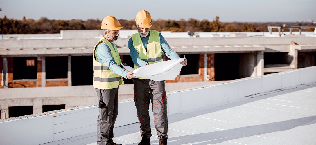 Construction professionals reviewing plans on a rooftop.