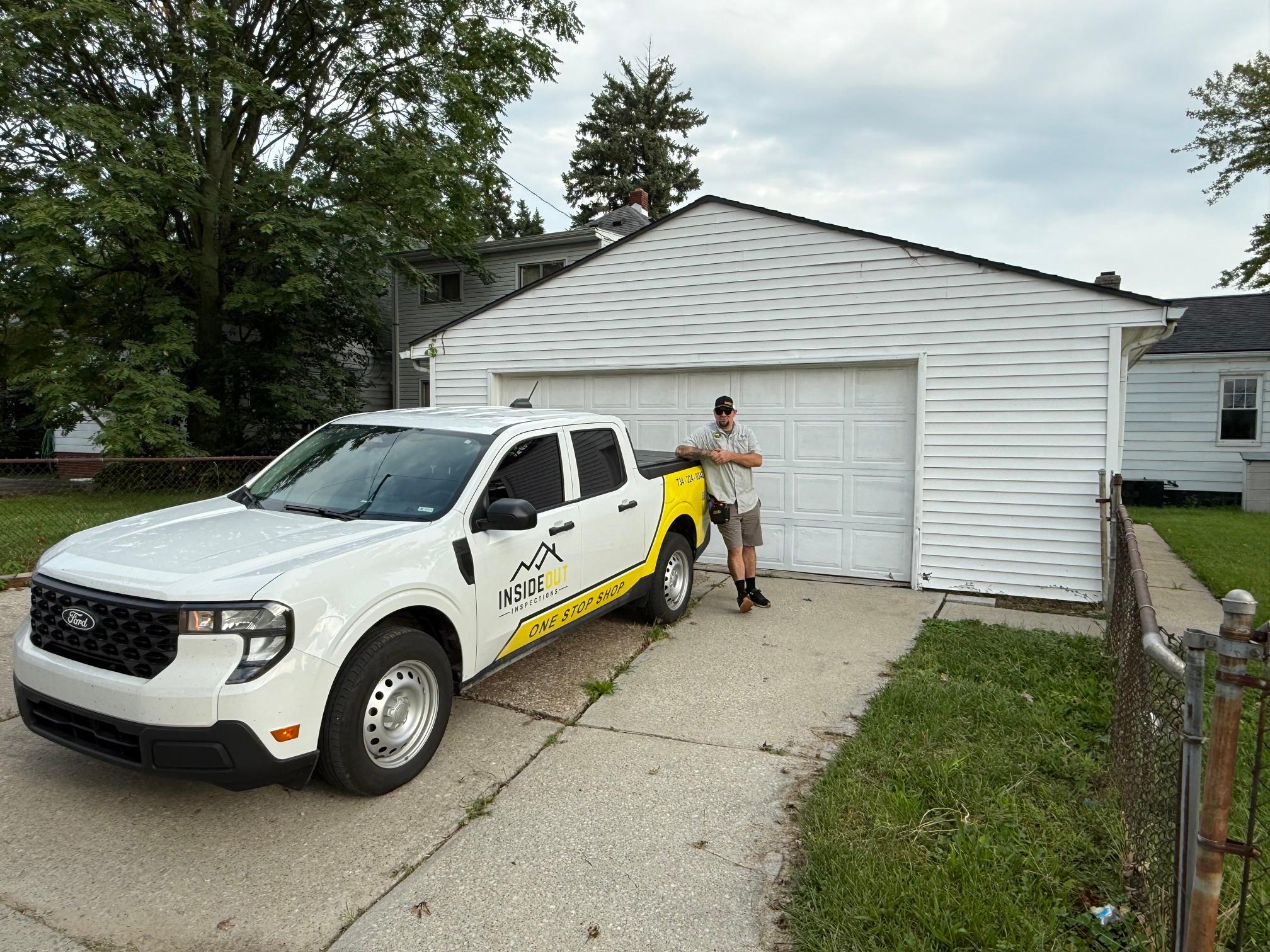 Home inspector leaning against a white "Inside Out Inspections" company pickup truck parked in a driveway.