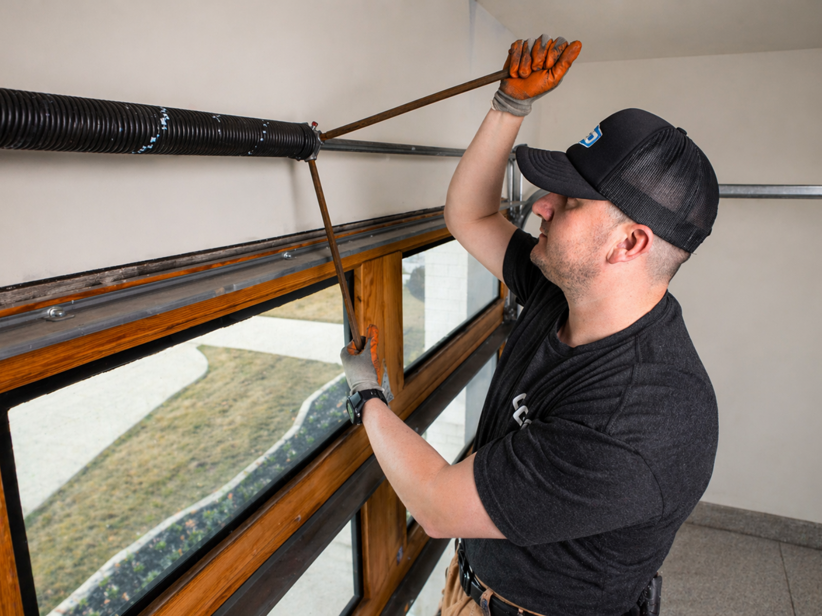 An OGD technician performs a garage door spring repair using winding bars.