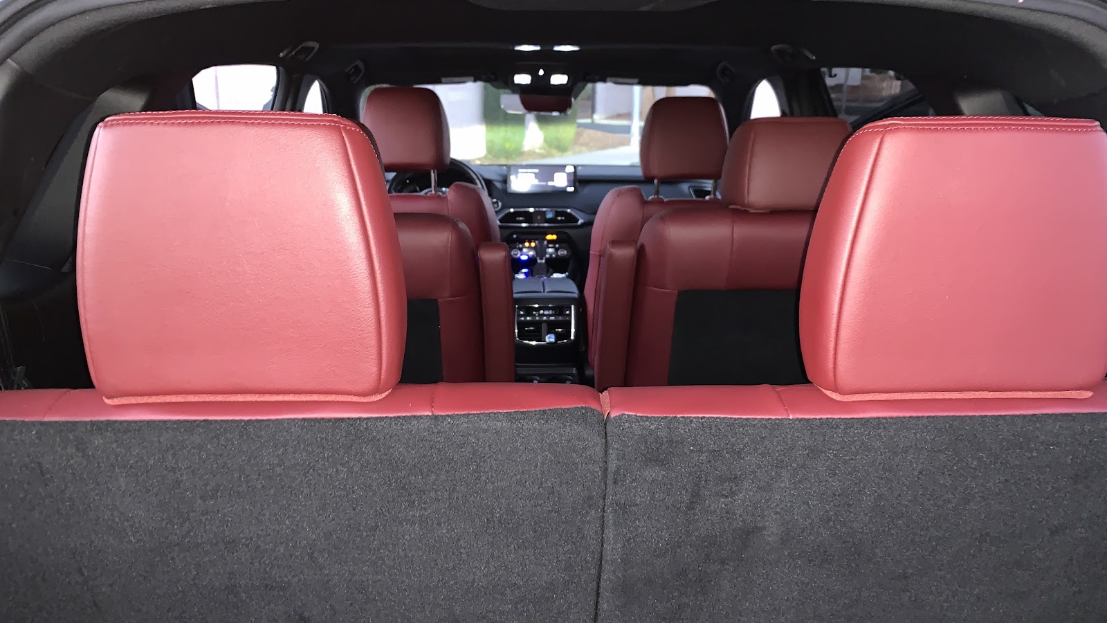 The interior of a car is shown, focusing on the rear seats and dashboard. The seats are upholstered  