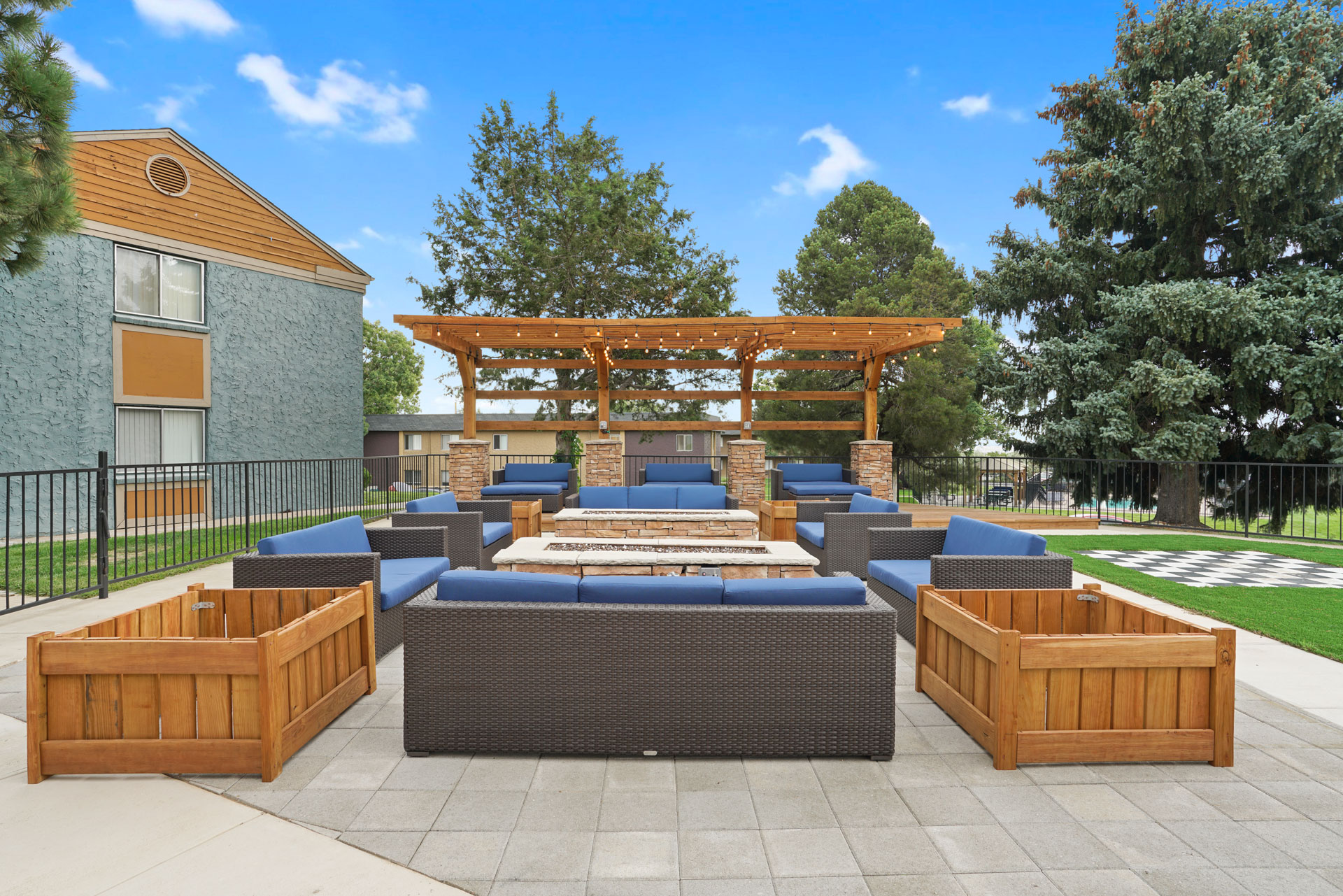 A wooden pergola is situated above a blue couch and a wooden table.