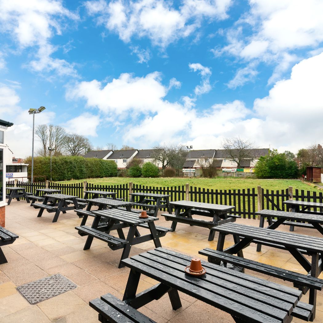 Spacious outdoor seating area with picnic benches, ideal for enjoying drinks and socialising outside.