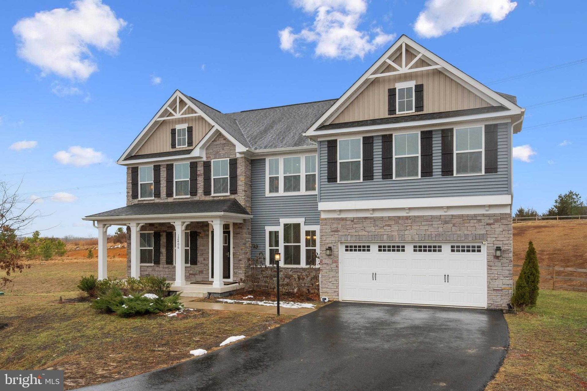 Spacious two-story suburban home with mixed materials facade, large garage, front porch, and wide driveway, reflecting modern residential construction focused on space, comfort, and visual appeal.