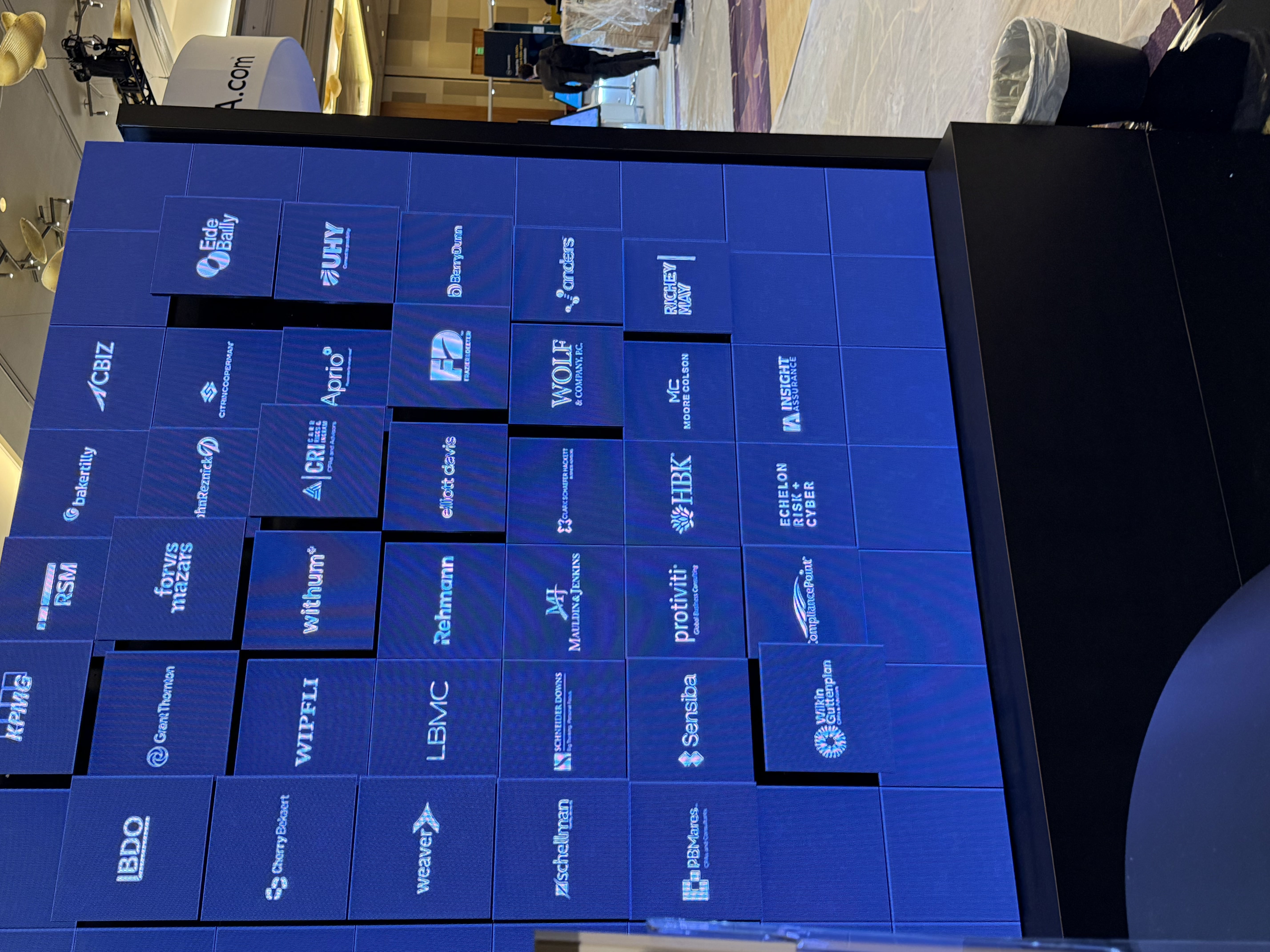 Custom blue display wall featuring illuminated brand graphics and a grid of presentation panels for an interactive exhibit environment.