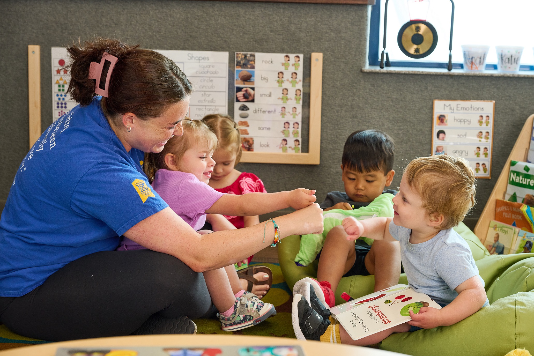 A childcare teacher reading to toddlers at New Horizon Academy Parker.