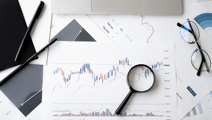 Printed graphs and a magnifying glass spread out on a desk.