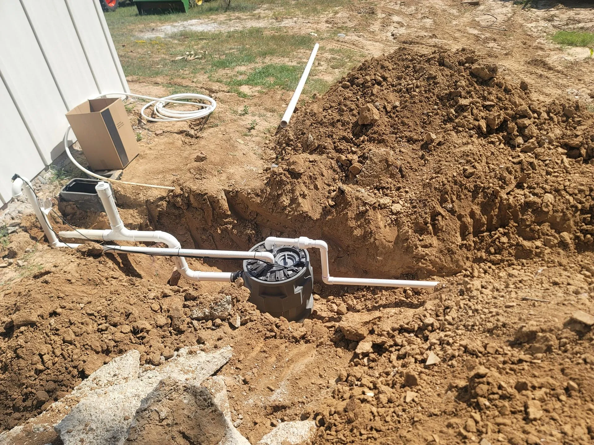 Newly installed underground plumbing system with PVC piping and sewer basin demonstrates professional drainage installation, precise excavation, quality workmanship, and dependable underground plumbing infrastructure for residential property construction projects.