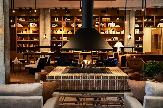 The lobby library at The Junto, with floor to ceiling bookshelves and a central fireplace. 