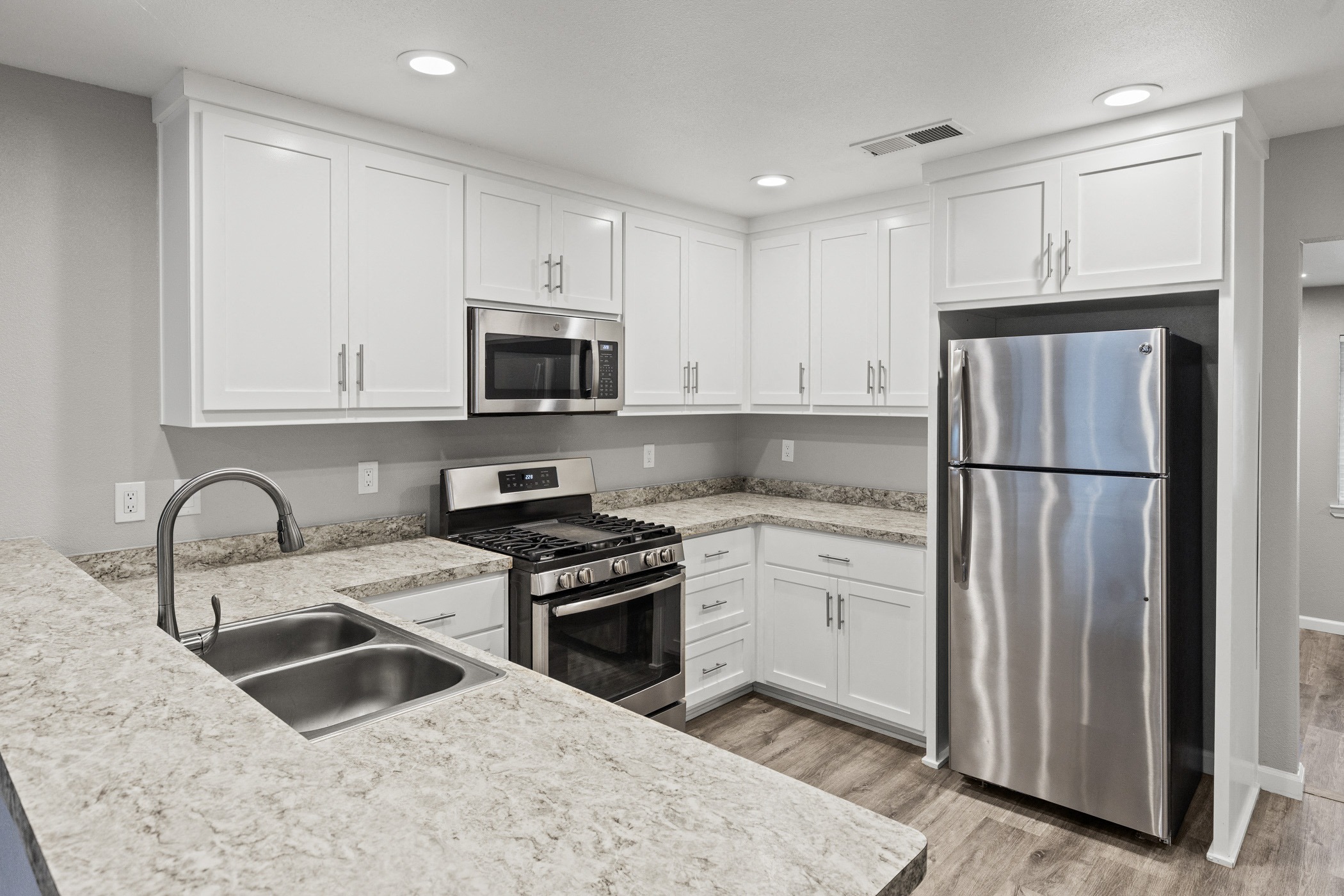 A kitchen with white cabinets and a stainless steel refrigerator.