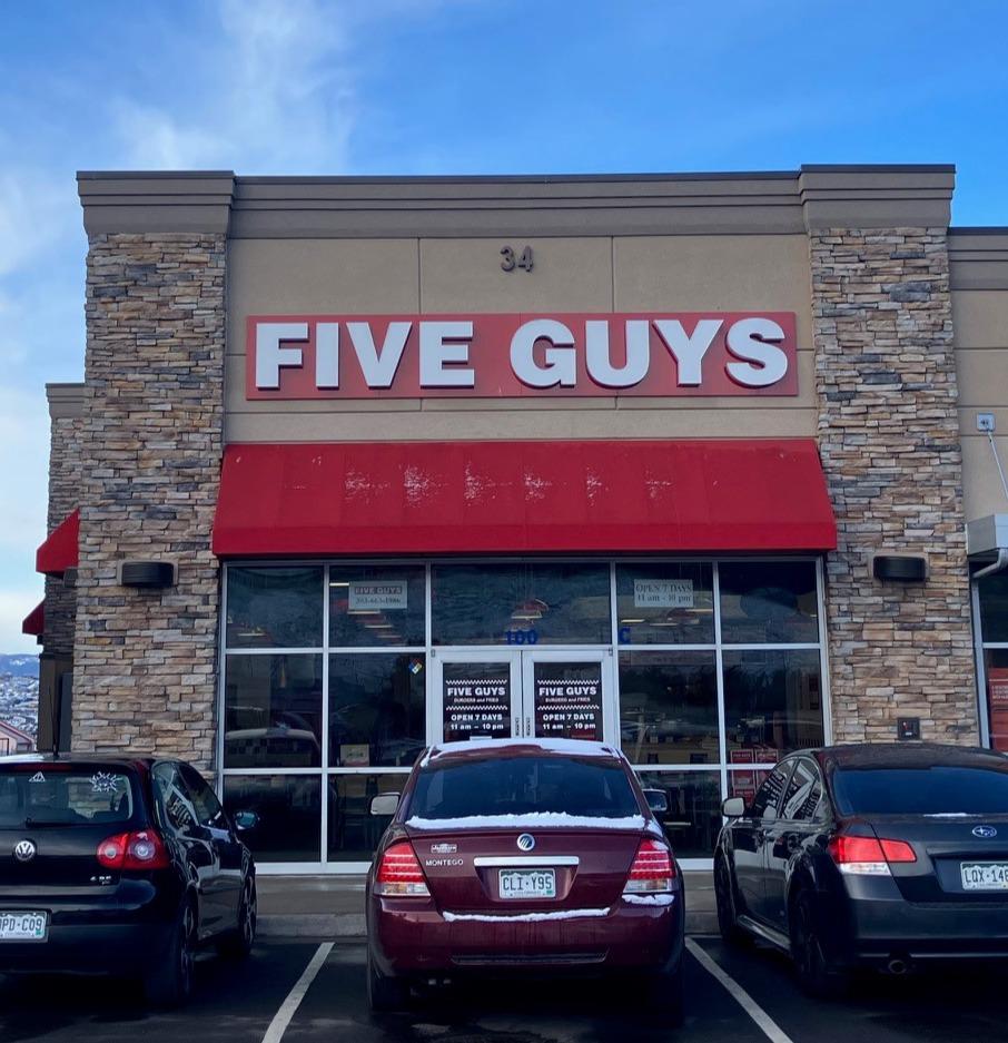Exterior photograph of the entrance to the Five Guys restaurants at 34 East Allen Street in Castle Rock, Colorado.