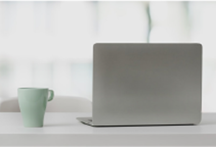 A laptop next to a mug of coffee.