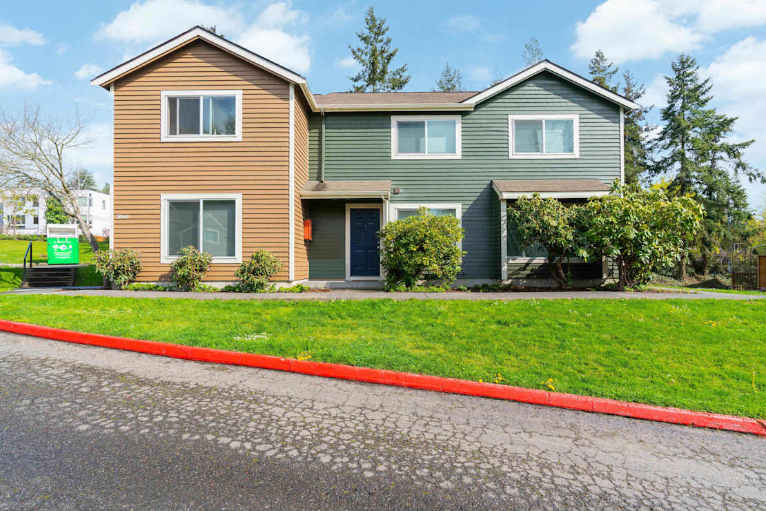 Exterior of apartment building and green grass on the side of a road