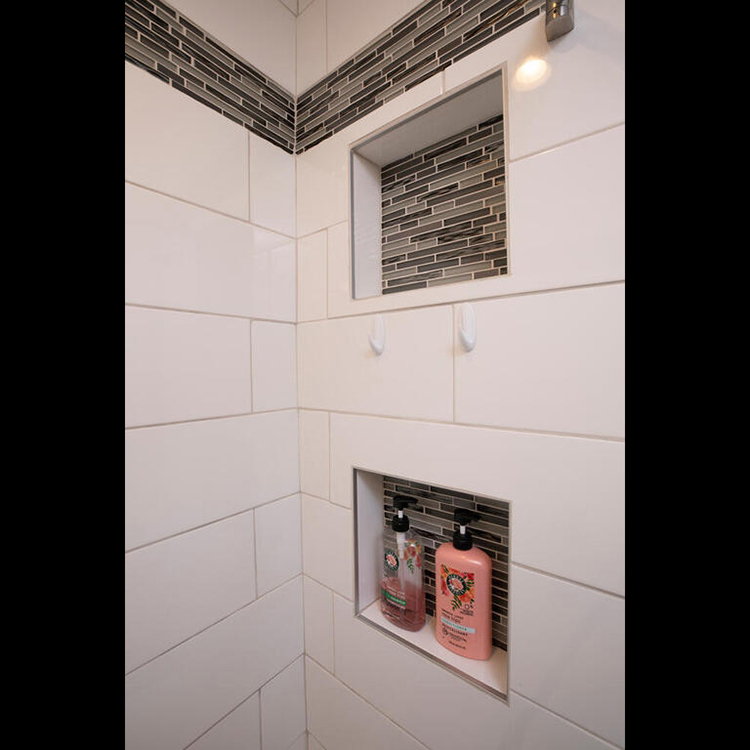ZimmTown Construction’s bathroom remodel showcases a beautifully tiled shower with modern fixtures, offering a sleek and refreshing design. Thoughtful details, from stylish tilework to efficient storage, create a functional and inviting space for everyday comfort.