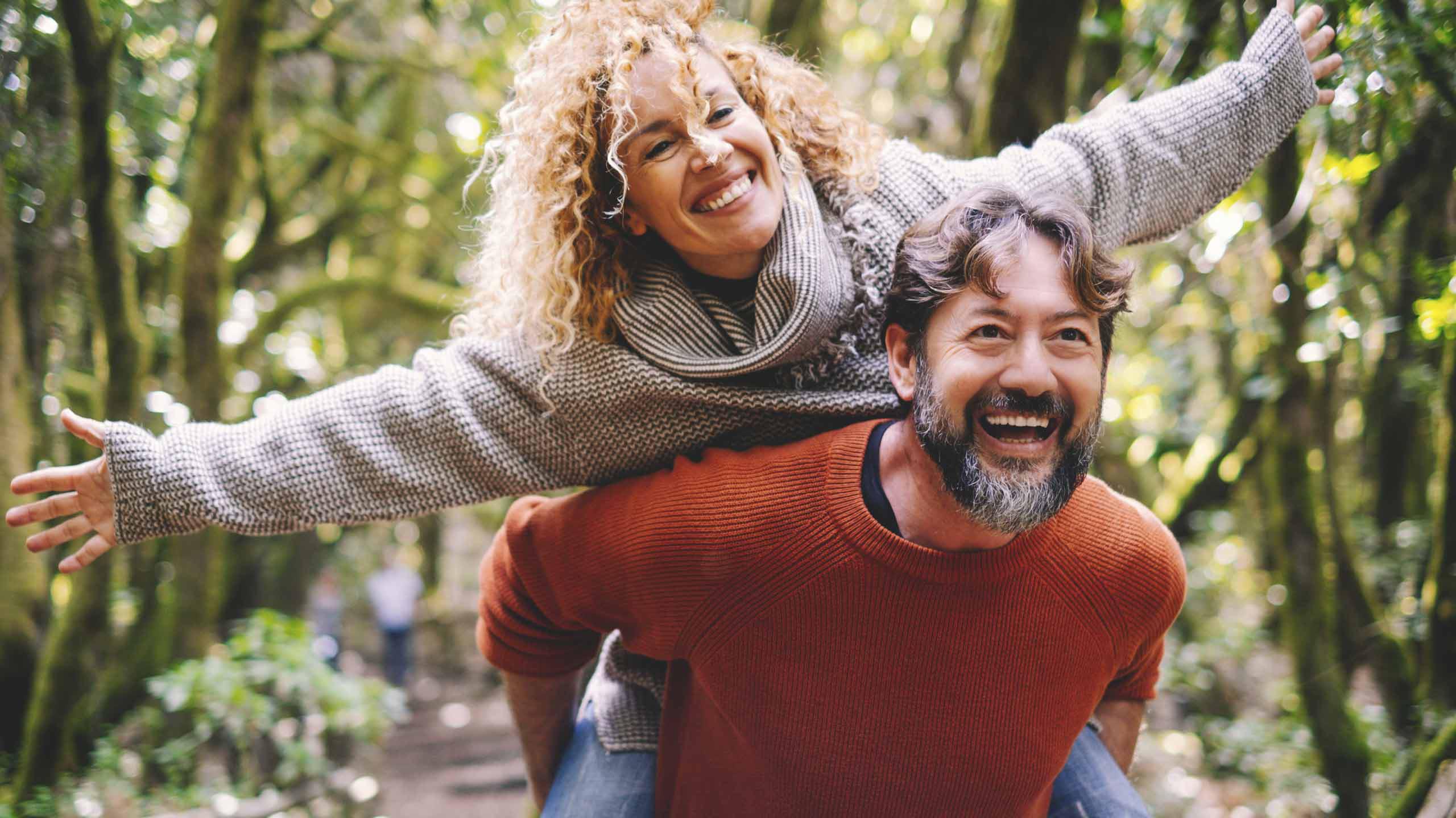 Woman smiling riding piggyback on man