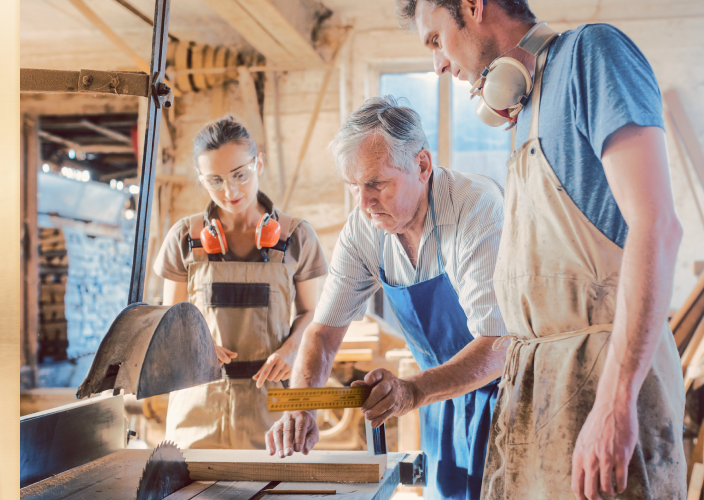Three people working in a woodshop.