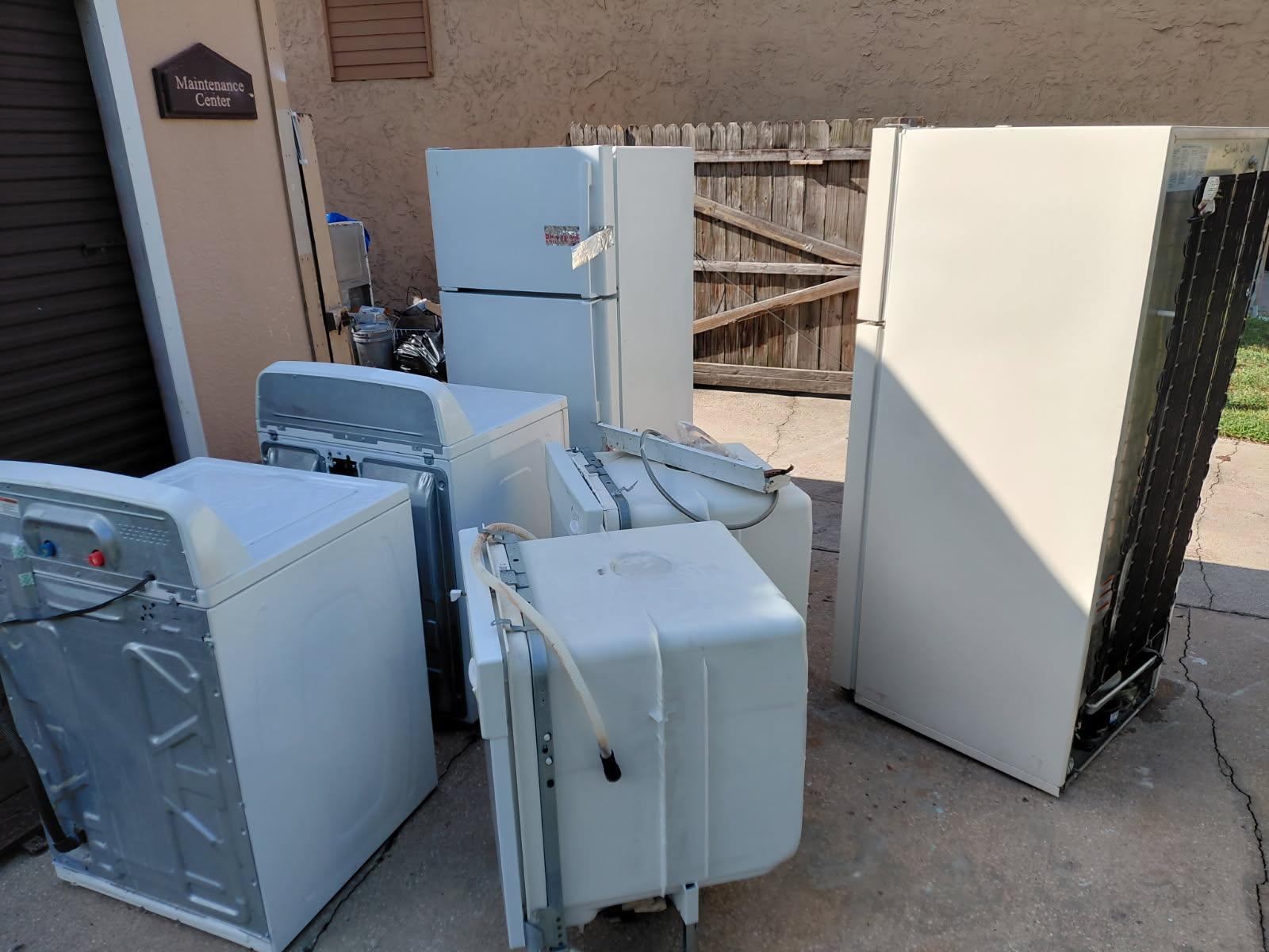 Several old white major household appliances, including refrigerators, washers, and dishwashers, par 