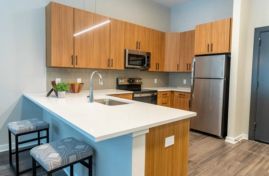 A kitchen with a white countertop and wooden cabinets 