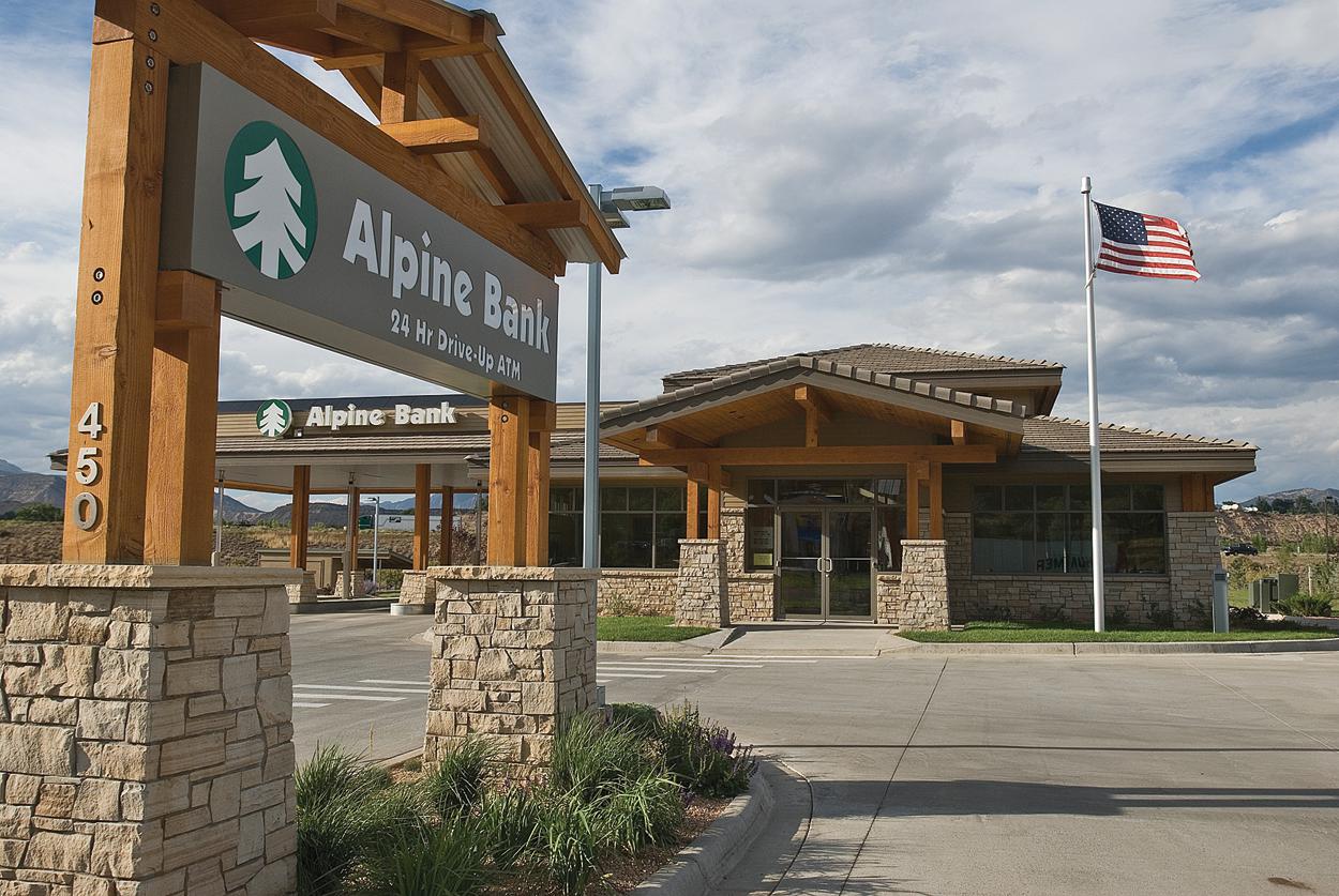 Showcasing Mappco Construction's excellence, this photo features the Alpine Bank building, an example of commercial architecture. The structure is distinguished by its rustic stone and wood elements, with a 24-hour drive-up ATM service advertised under a timber-framed sign, reflecting Mappco’s commitment to blending functionality with aesthetic appeal in business construction.