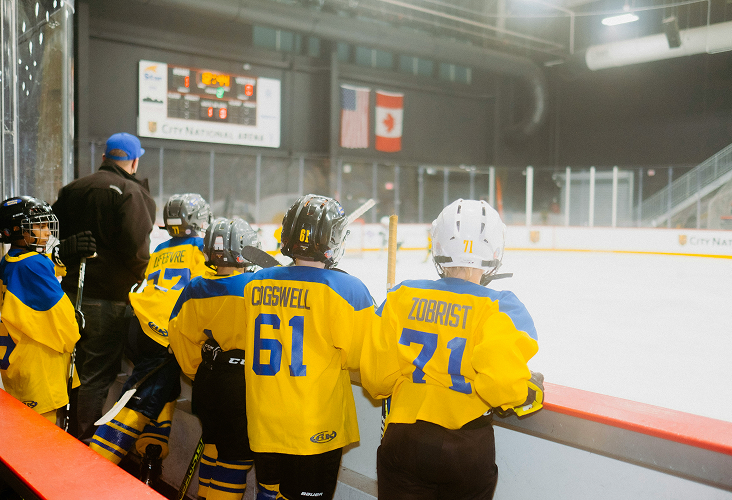 Young minor hockey players cheering on their teammates from the bench.