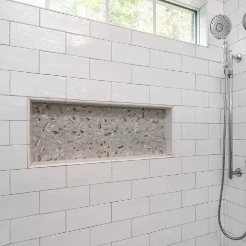 Custom walk-in shower renovation near Badin Lake, North Carolina featuring white subway tile, recessed niche shelving, and modern fixtures. This bathroom remodel showcases precision tile work and high-quality residential remodeling craftsmanship.