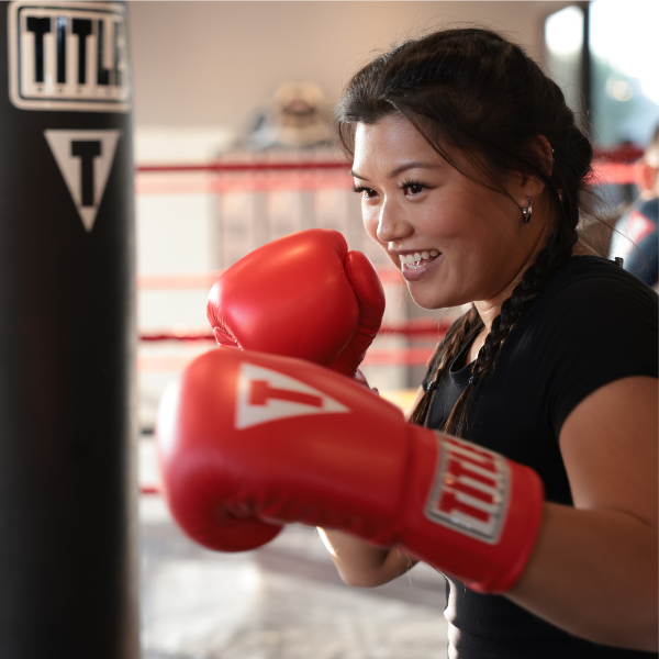 Woman with TITLE Boxing gloves training at TITLE Boxing Club gym.