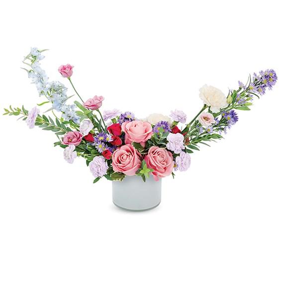 Garden Bliss Bouquet - Feelings of being at a garden party is reminicent of this wonderous bouquet boasting medium pink roses, hot pink roses, lavender mini carnations, pink mini carnations, peach carnations, purple monte casino, blue delphimium in a stylish milk glass cylinder.