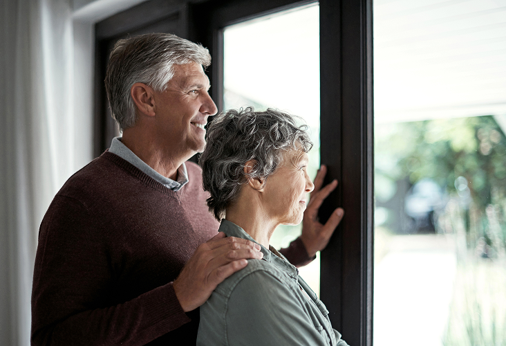 A husband and wife looking out of a window together.