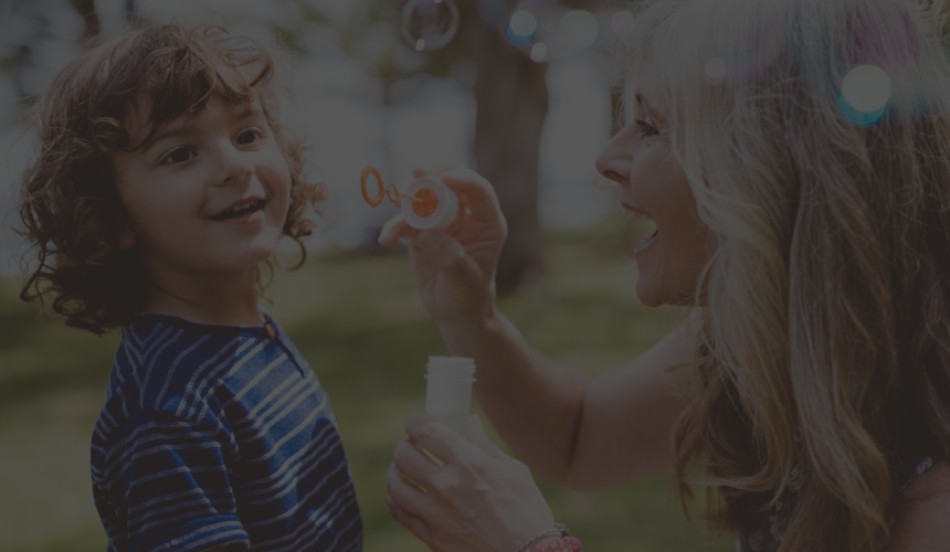 A woman blowing bubbles with a child.