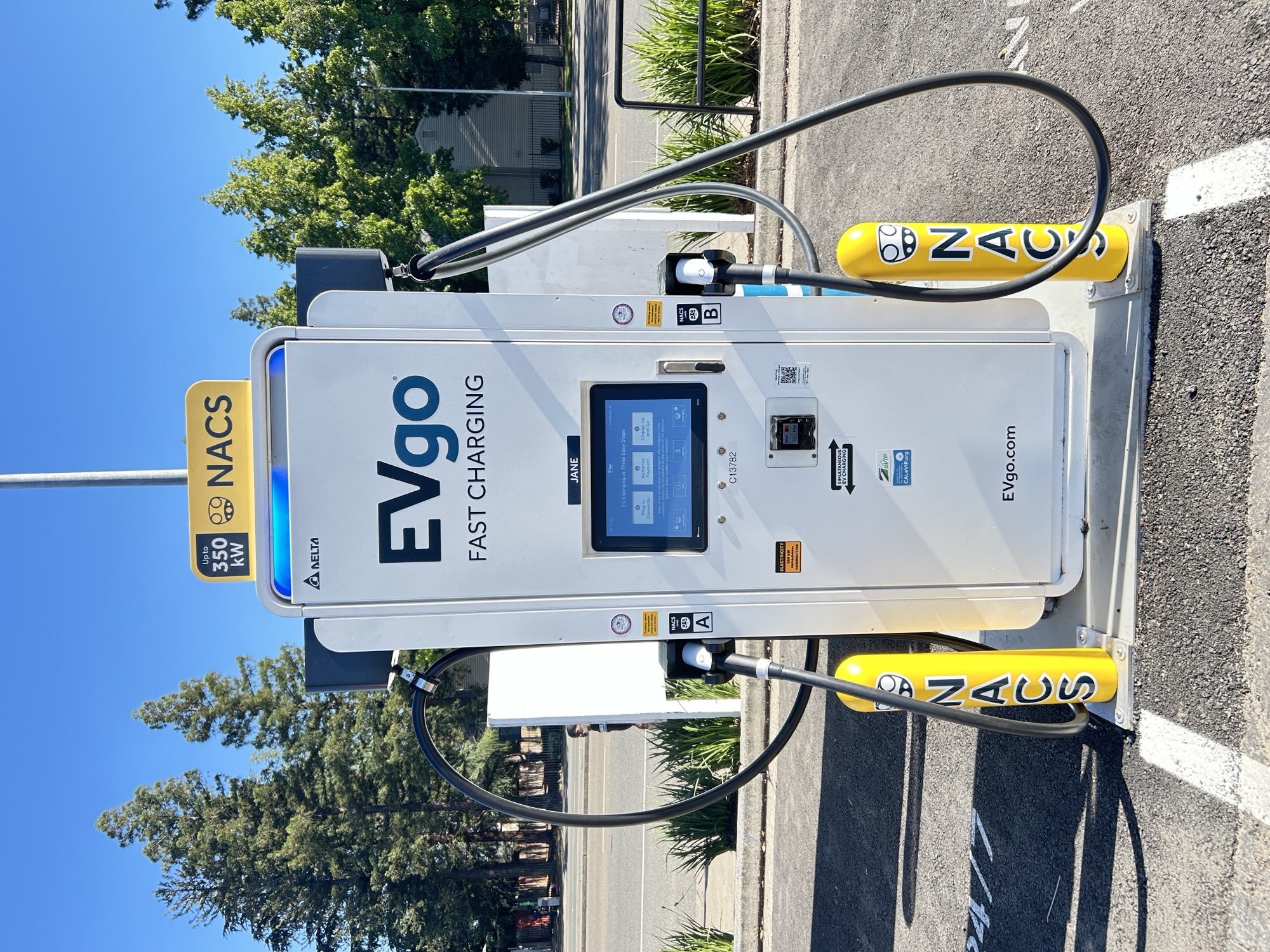 NACS EVgo fast charging unit installed in marked parking space at a public charging station, with EV 