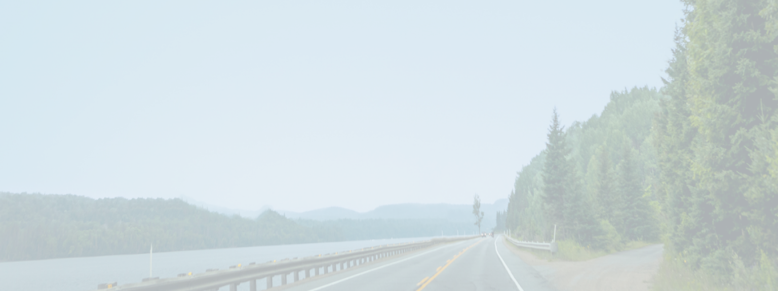 Open road with a river on one side and forest on the other.