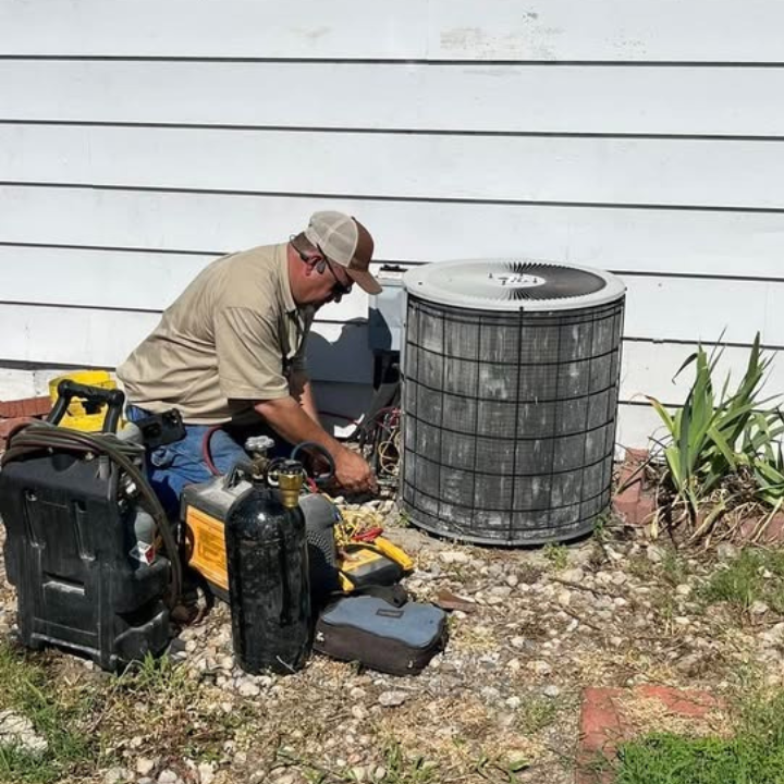 Technician recovering refrigerant before opening an older air conditioning system.